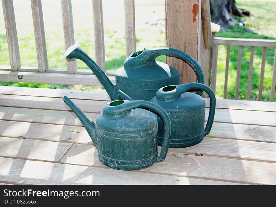 Three blue watering cans on front porch