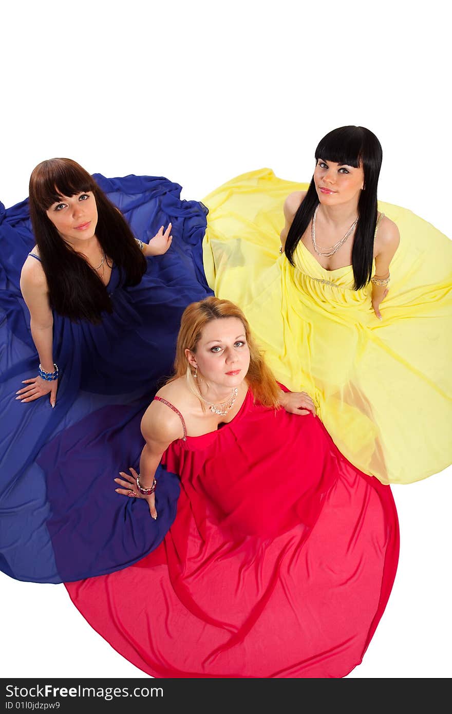 One blond and two brunette woman in red, blue, and yellow dresses. One blond and two brunette woman in red, blue, and yellow dresses