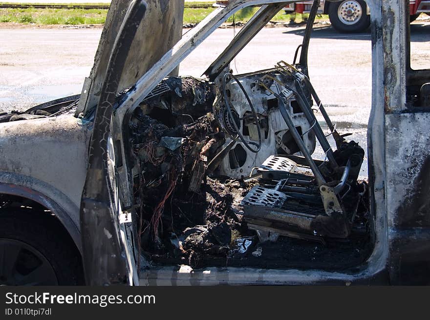 Interior of a burned out truck with fire truck in the background. Interior of a burned out truck with fire truck in the background