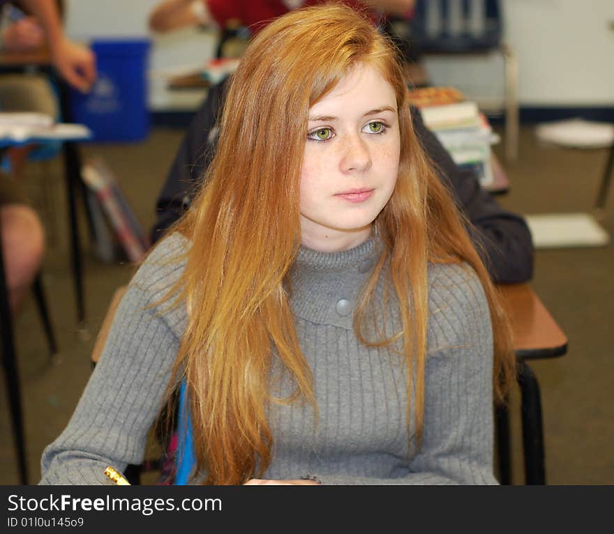 Strawberry blonde teenager taking notes in a classroom. Strawberry blonde teenager taking notes in a classroom