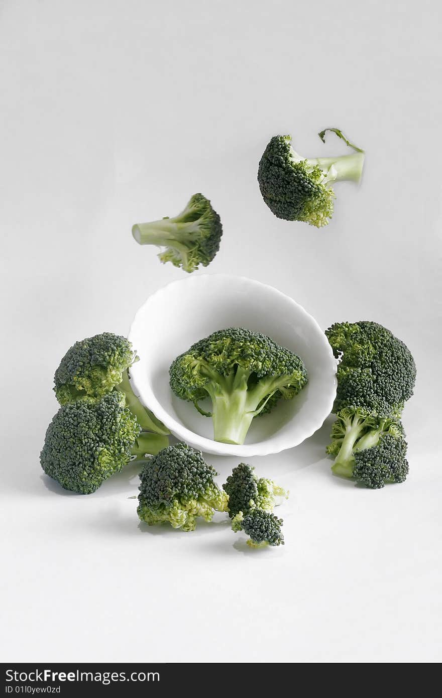 Green fresh broccoli flying around white plate