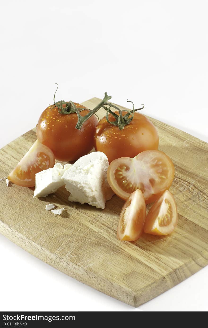 Fresh sliced tomatoes on a bread board with feta cheese