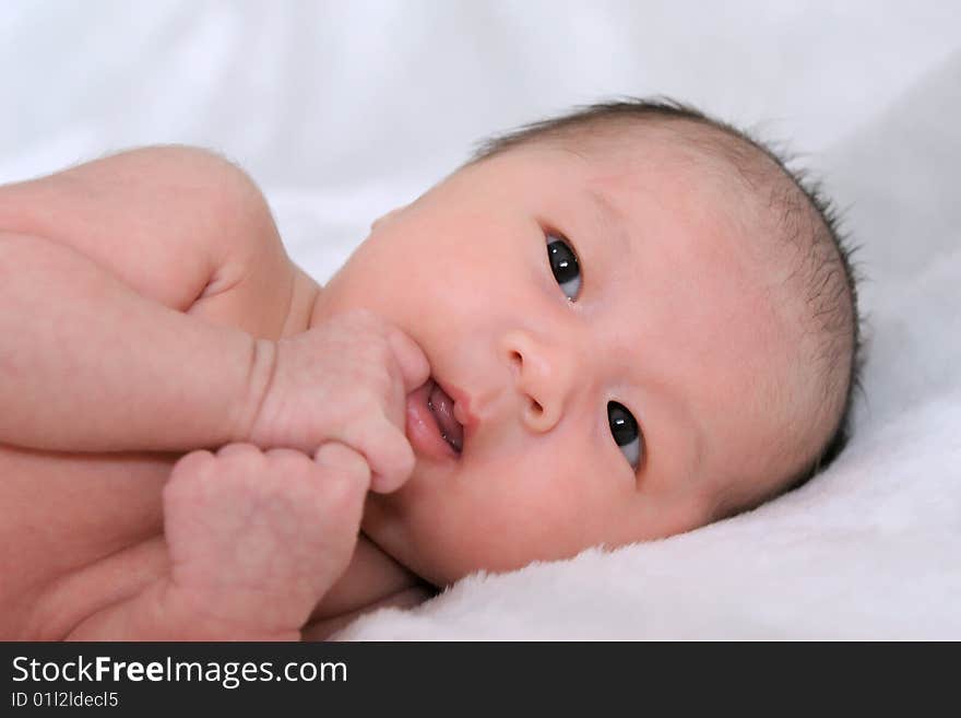 Portrait of beautiful thoughtful baby on white bedsheet