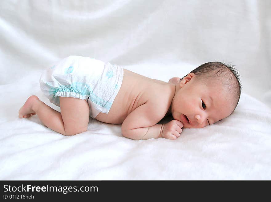 Portrait of beautiful thoughtful baby on white bedsheet