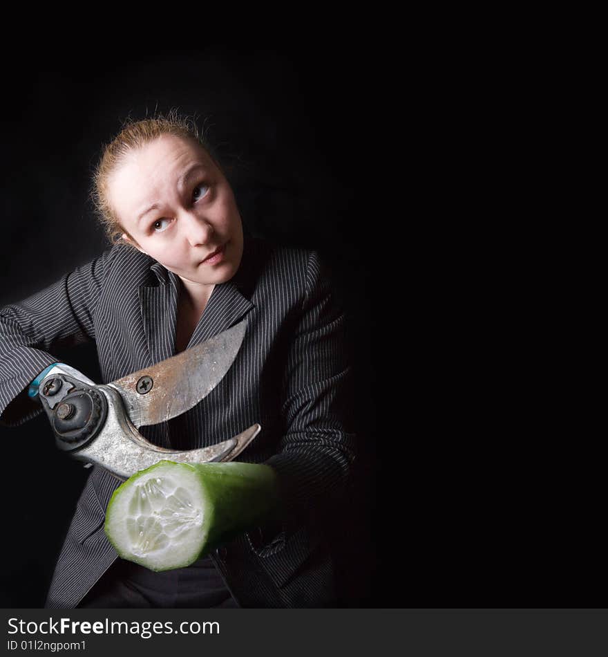 Female with gun and cucumber instead of hands against the black background. Female with gun and cucumber instead of hands against the black background