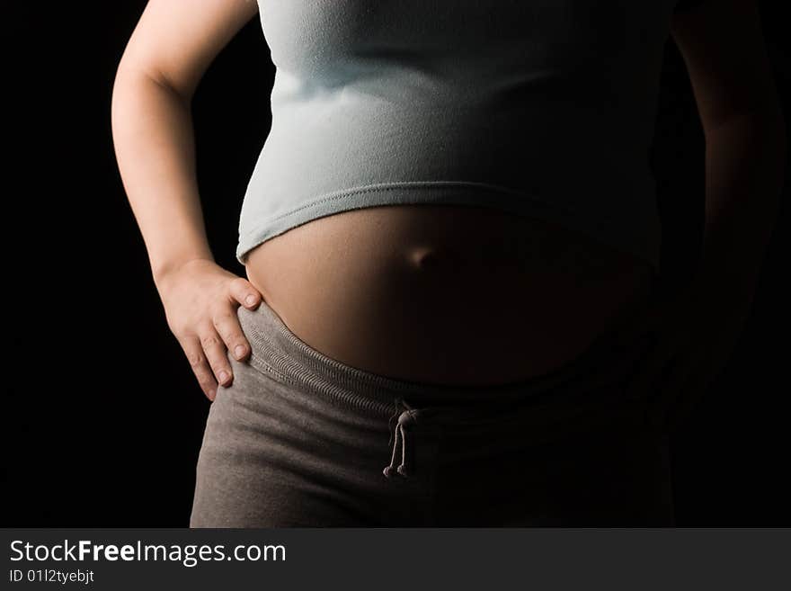 Pregnant woman's abdomen side lit on black. Pregnant woman's abdomen side lit on black