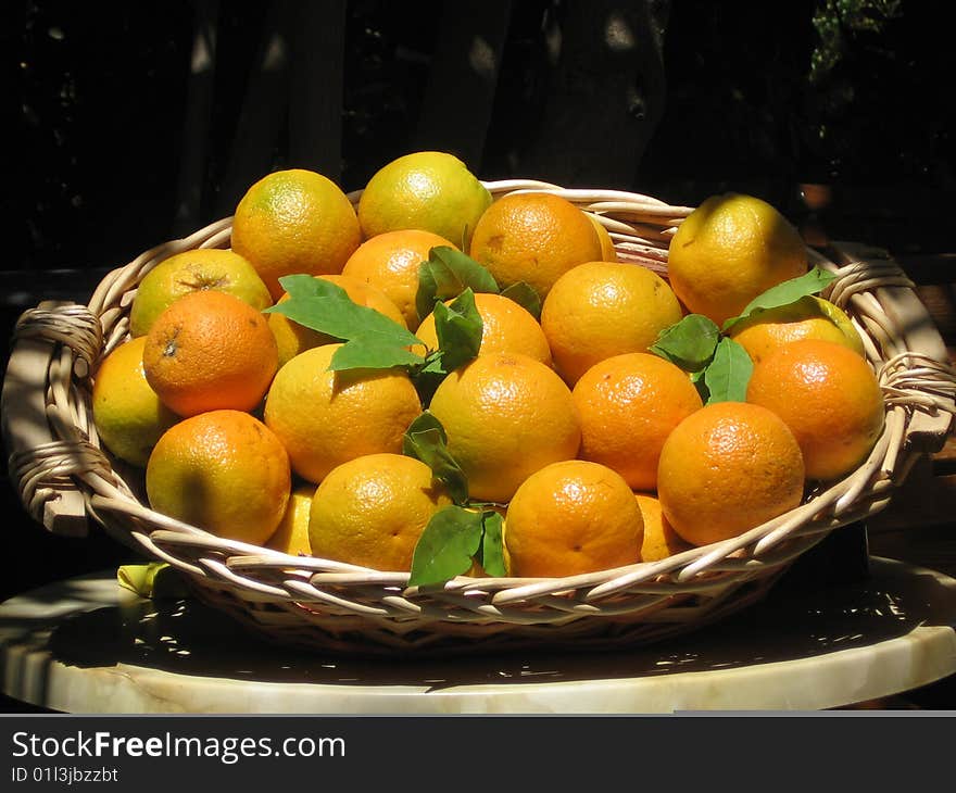 Oranges with green foils in a basket on a hot sunny day in greece. Oranges with green foils in a basket on a hot sunny day in greece.