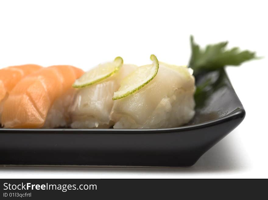 A set of sushi on a black plate with wasabi and gari, isolated on a white background, close-up. A set of sushi on a black plate with wasabi and gari, isolated on a white background, close-up.