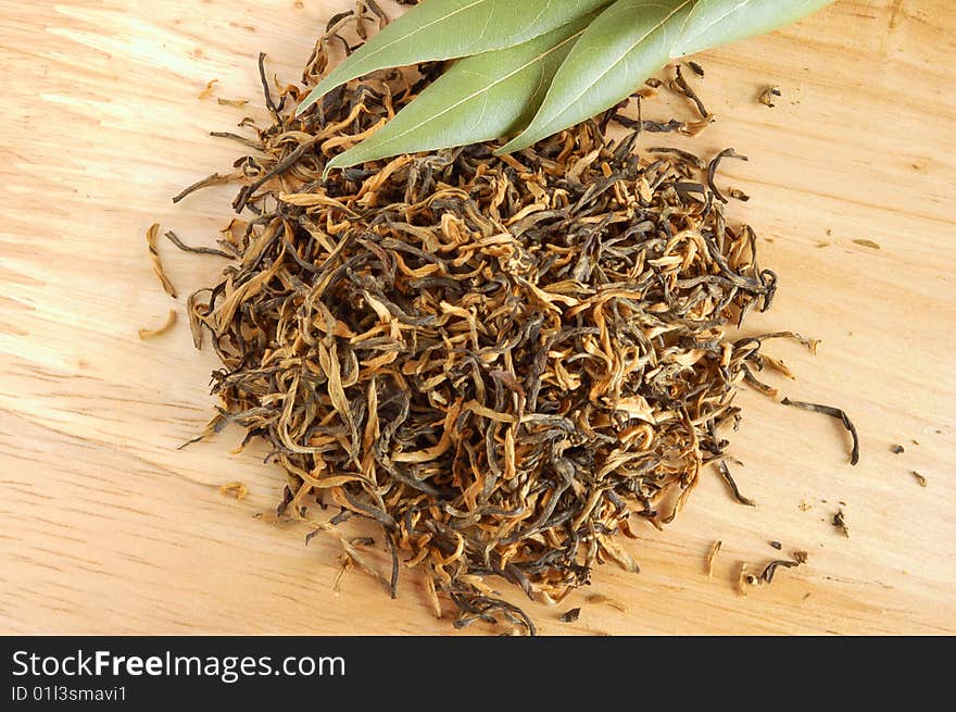 Aromatic dry yellow tea and fresh leaves on wooden board