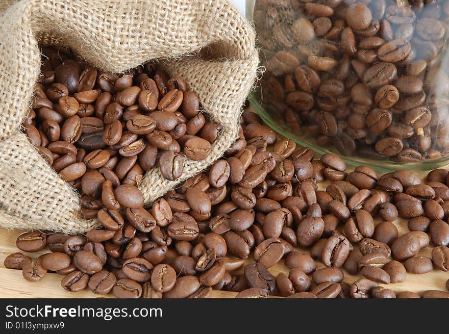 Coffee beans in canvas sack on wooden background. Coffee beans in canvas sack on wooden background