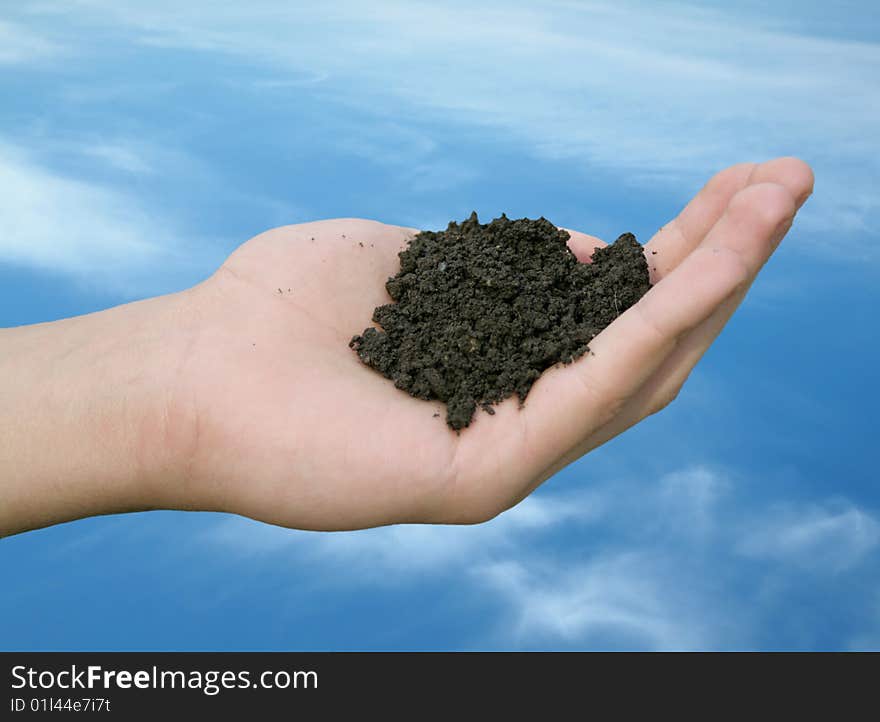 Soil strewing hand on cloudy sky background. Soil strewing hand on cloudy sky background.