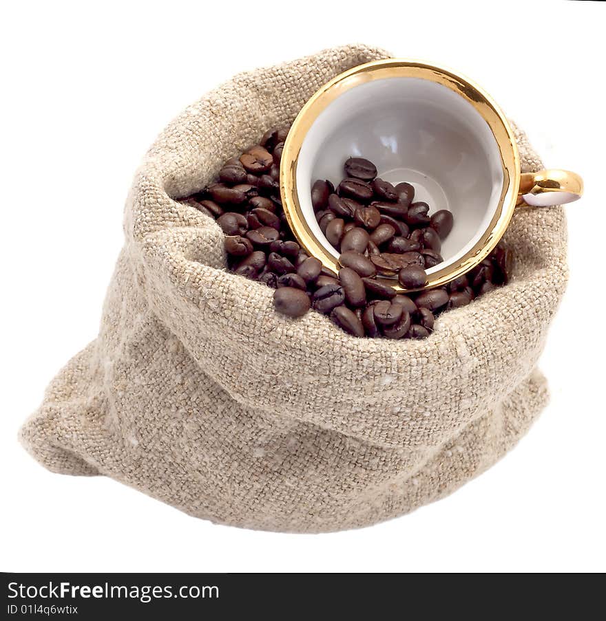 Cup lies in a sack with coffee grains is isolated on white