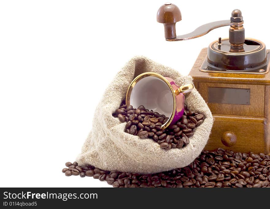 Coffee grinder, cup lies in sack with coffee grains is isolated on white