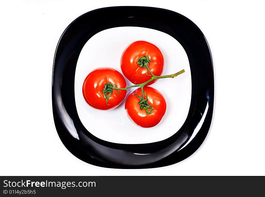 Bunch of three tomato on black and white plates. Bunch of three tomato on black and white plates