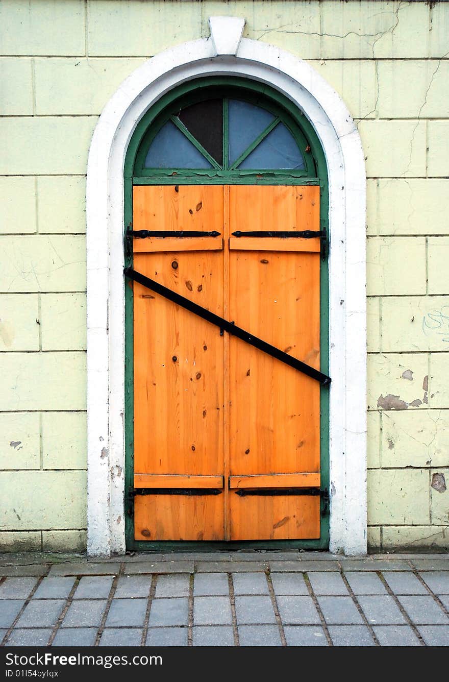 Wooden locked door with broken window crossed with metal board