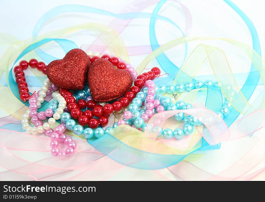 Composition of their two hearts, costume jewellery and ribbons on a white background. Composition of their two hearts, costume jewellery and ribbons on a white background