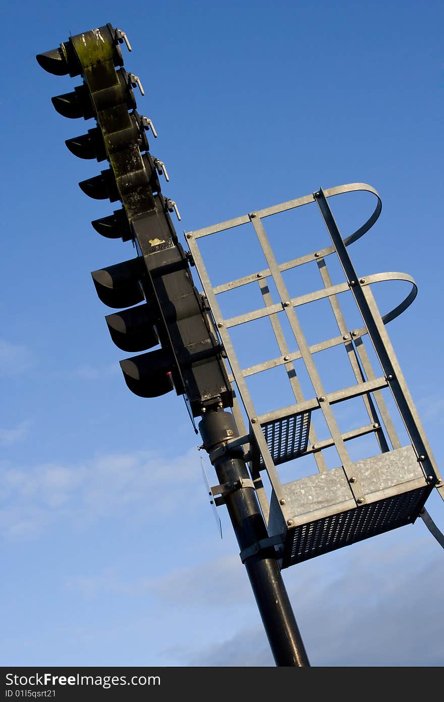 A black railroad semaphore and a metal platform. A black railroad semaphore and a metal platform