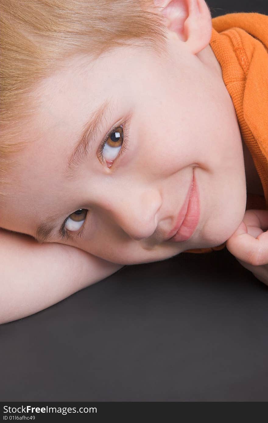 Friendly boy with an orange shirt against a black background