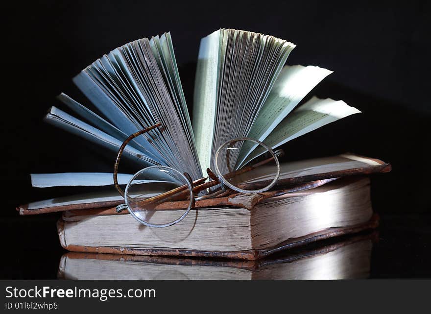 Two antique books with reverberation lying on dark background. Two antique books with reverberation lying on dark background