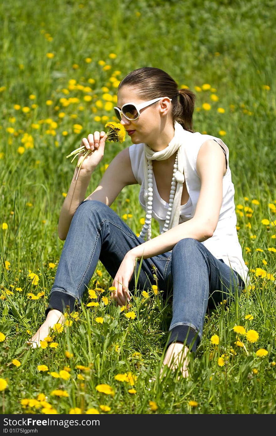 Beautiful young woman with sunglasses in nature smelling a flower. Beautiful young woman with sunglasses in nature smelling a flower