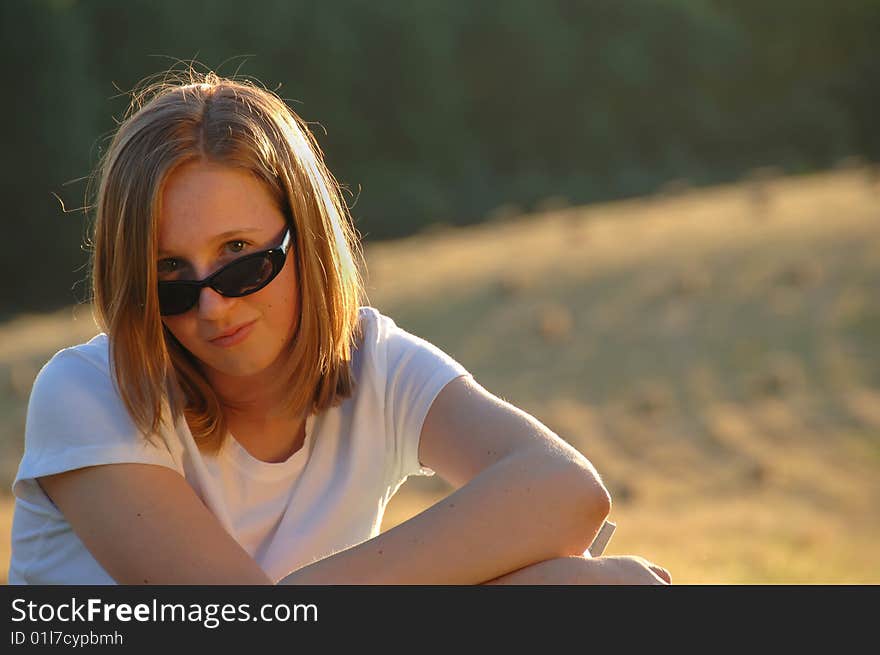 Portrait of a pretty teenage girl looking over her sunglasses. Portrait of a pretty teenage girl looking over her sunglasses.