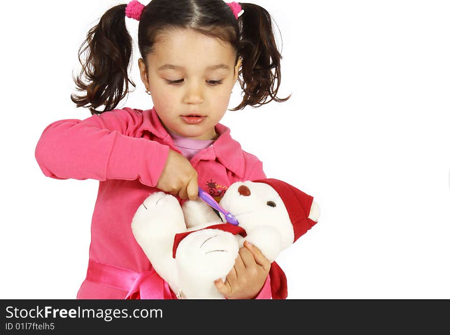 A little girl play brushing the teeth with a teddy bear isolated on white background