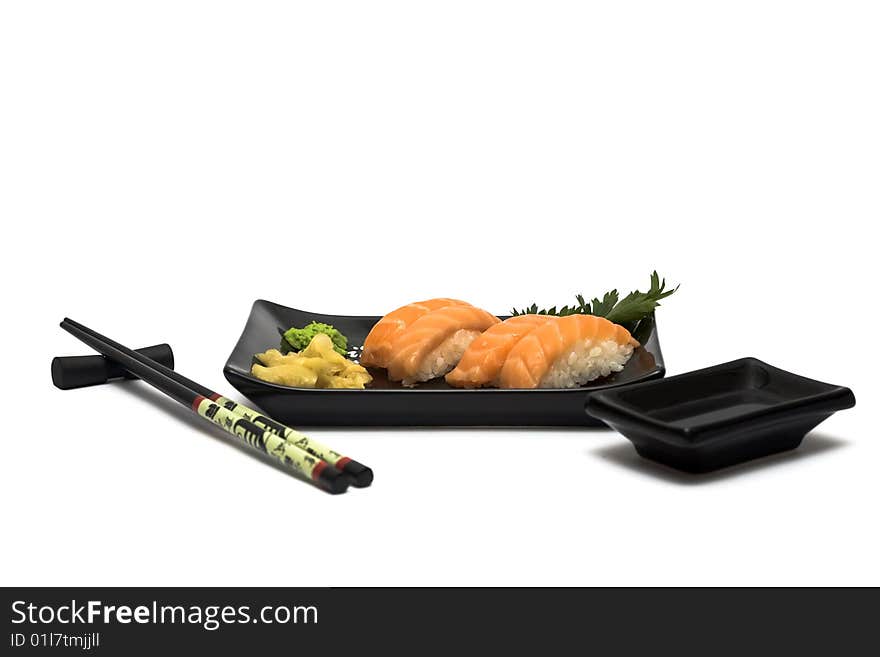 A set of sushi on a black plate with wasabi and gari, isolated on a white background, wish hashi ans soy sauce. A set of sushi on a black plate with wasabi and gari, isolated on a white background, wish hashi ans soy sauce.