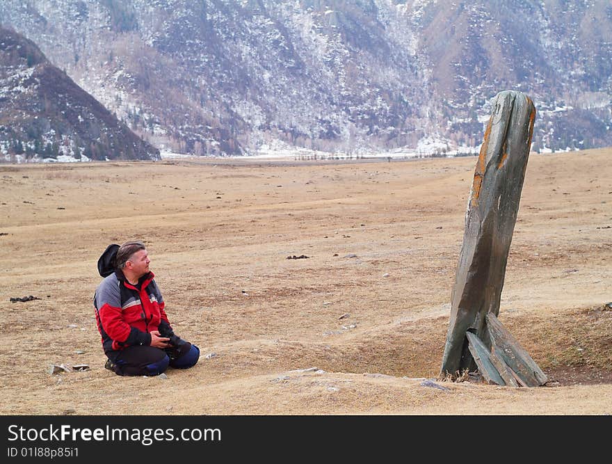 The man thinking kneeled befor ancient menhir. The man thinking kneeled befor ancient menhir