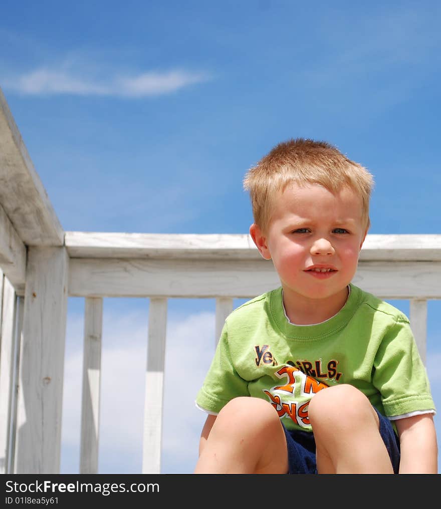 Boy sitting outside on white porch