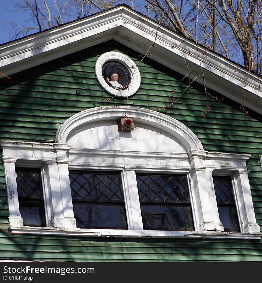 Old creepy house with a doll in the circle window. Old creepy house with a doll in the circle window