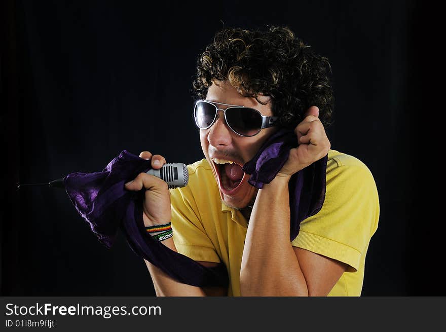 Portrait of a young man screaming with a microphone - isolated over black