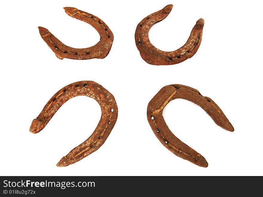 Four old rusty horseshoes on a white