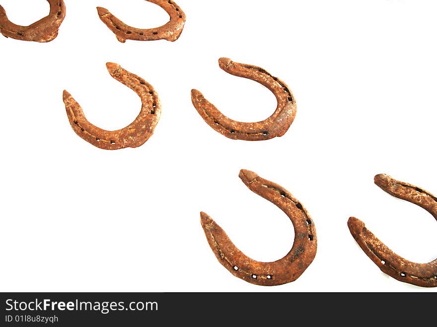 Two rows of old rusty horseshoes on white