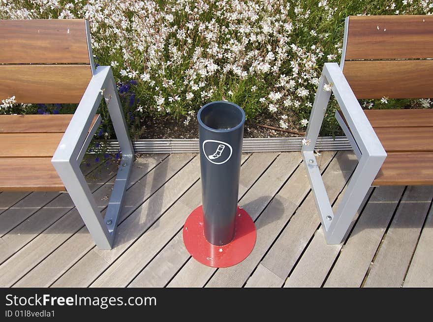 Ashtray in a public place with wooden benches and metal