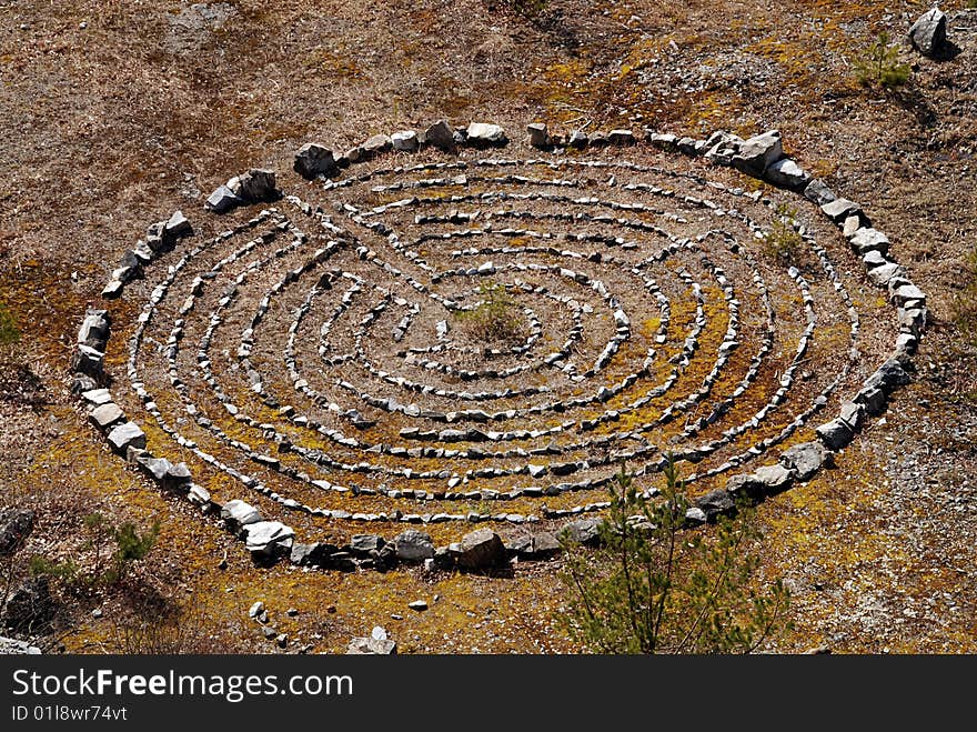 Maze from stones leading to a small pine reminds ancient mysterious buildings