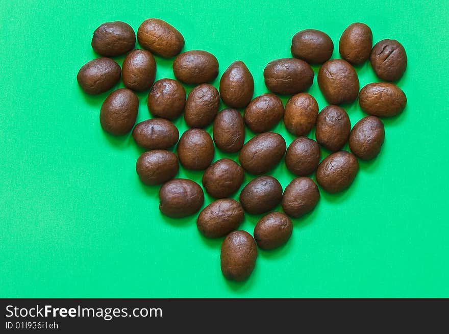 Heart made by coffee beans on green background. Heart made by coffee beans on green background