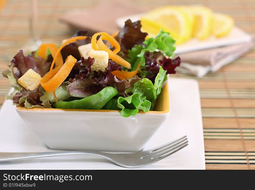 A white bowl of assortment type of lettuce salad