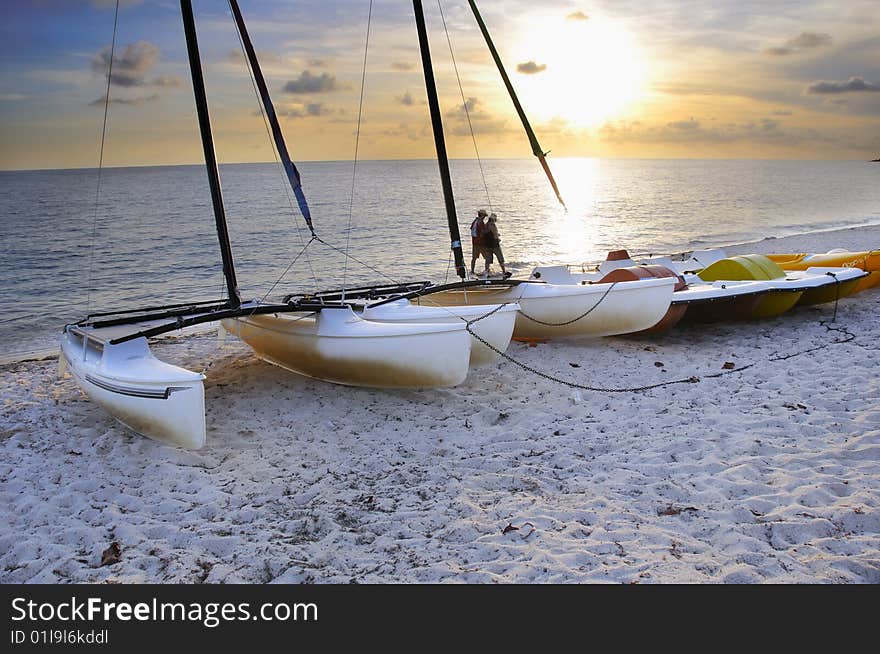 View of tropical beach at sunset with sailing boats on the sand. View of tropical beach at sunset with sailing boats on the sand