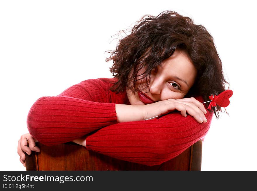 Closeup of a girl in red sitting on a chair and holding a little red heart