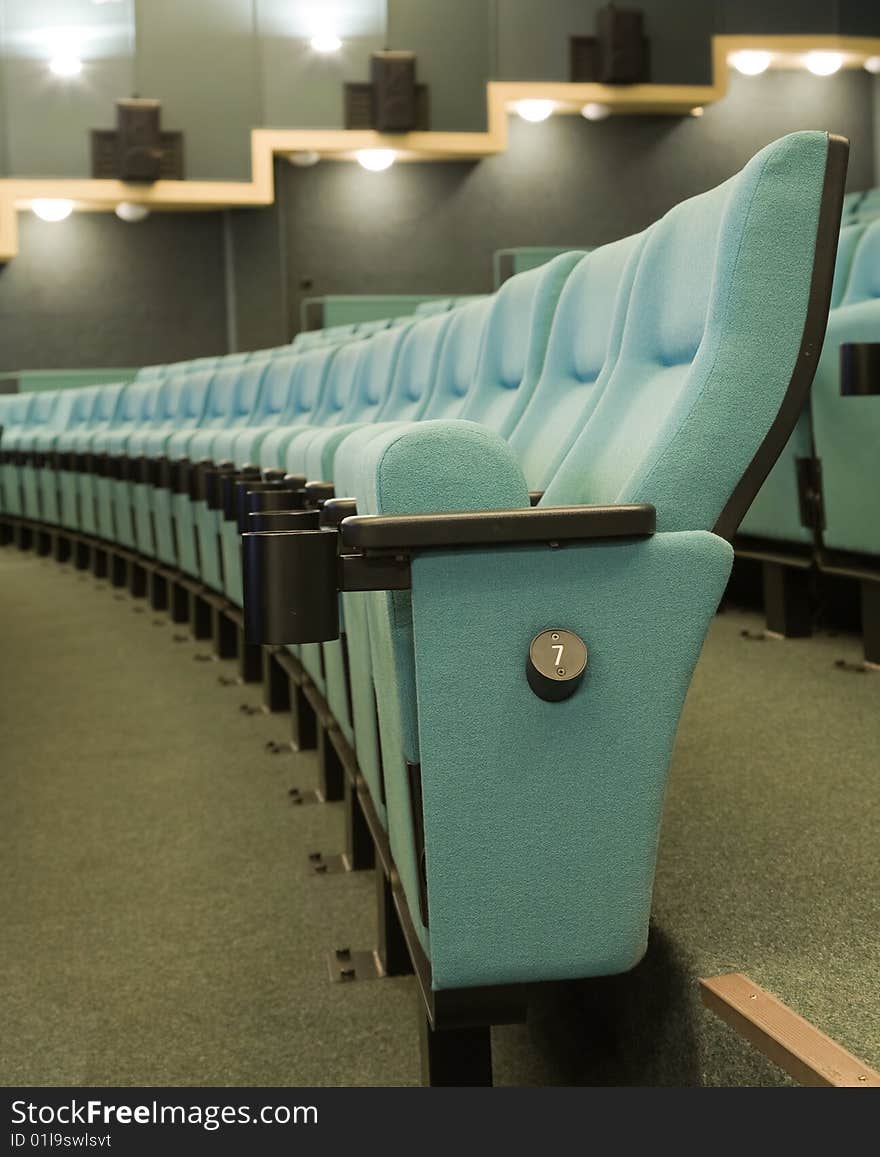 Row number seven. Row of green chairs in auditorium. Row number seven. Row of green chairs in auditorium.