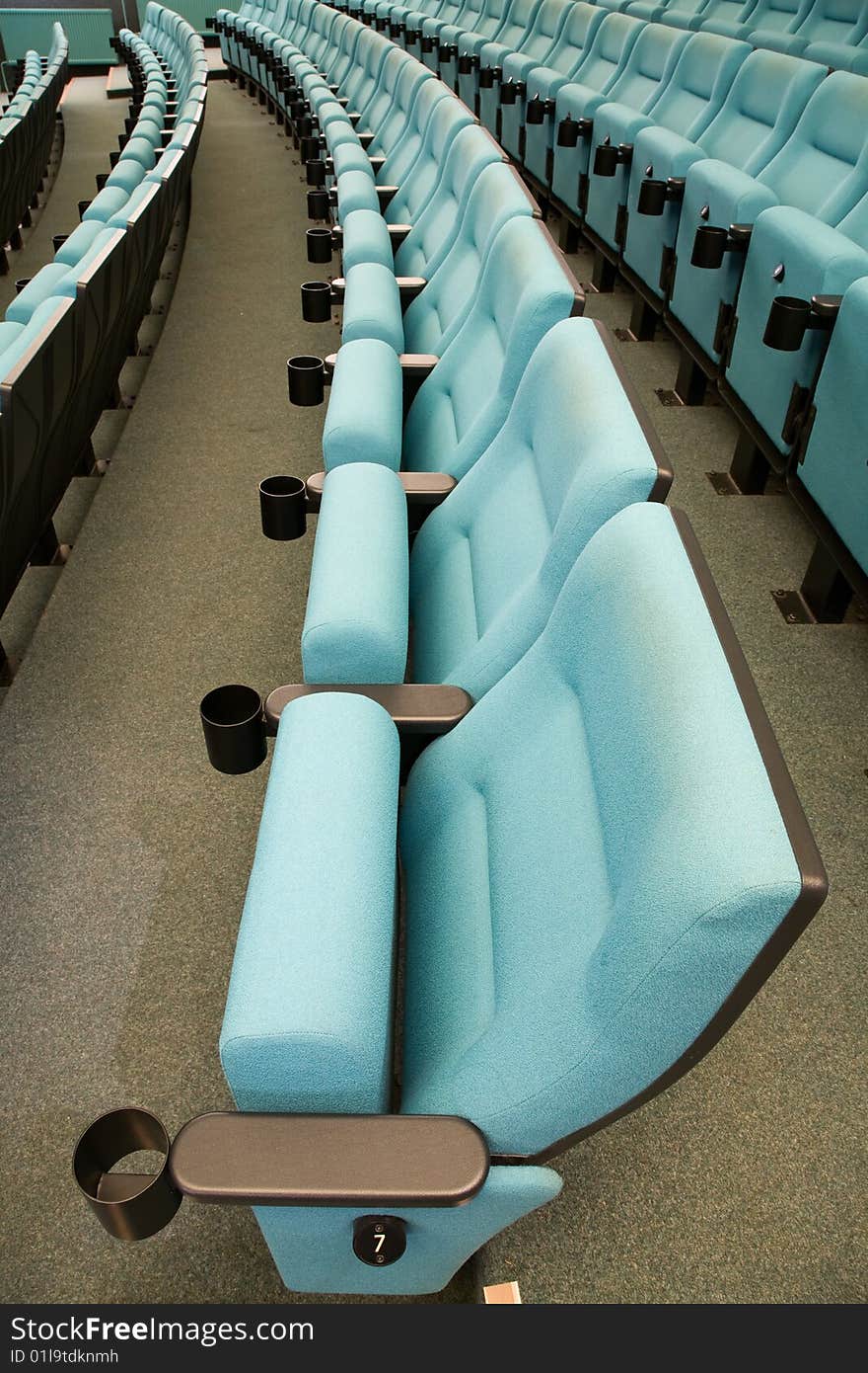 Row number seven. Row of green chairs in auditorium. Row number seven. Row of green chairs in auditorium.