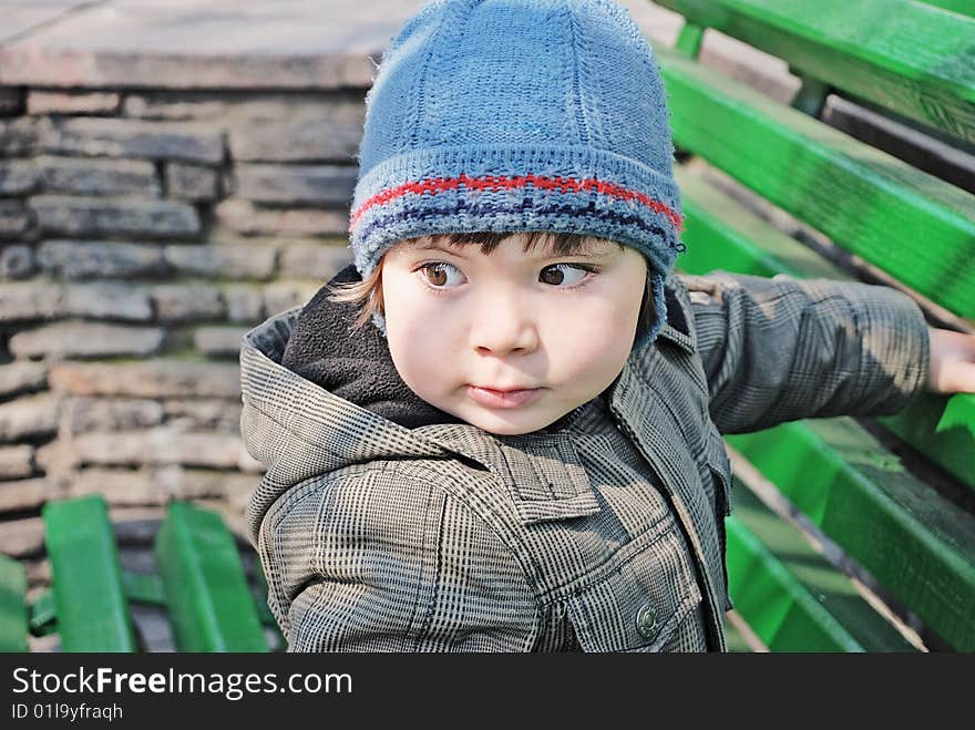 Boy of three years on a bench, looks around. Boy of three years on a bench, looks around