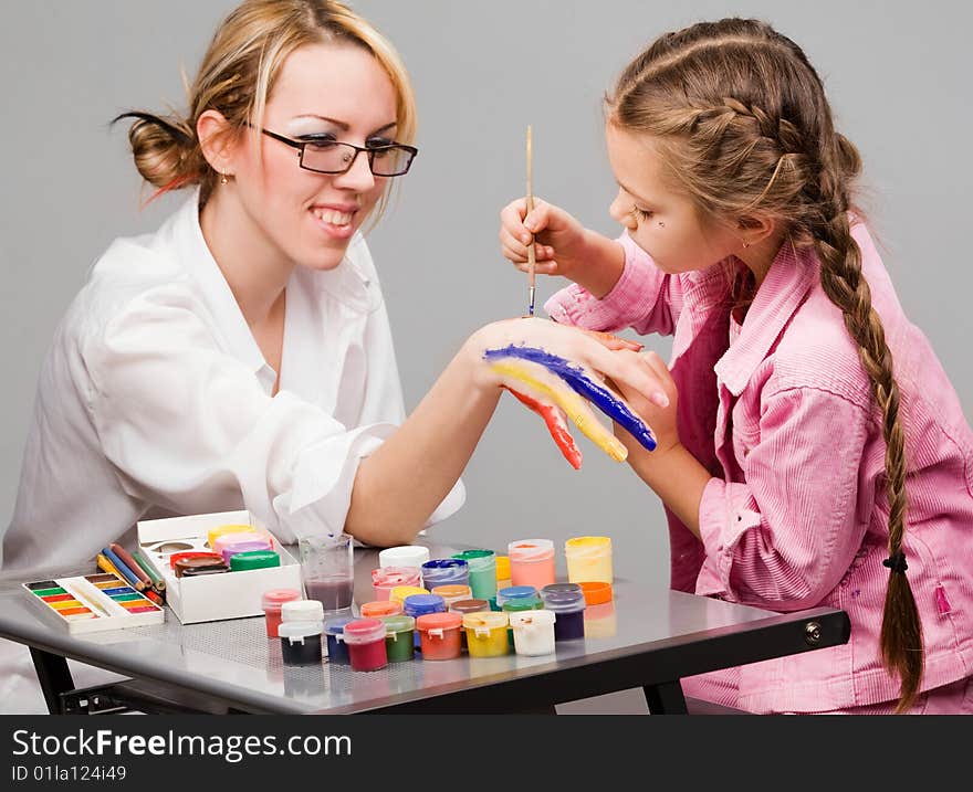 Little girl playing with mom, painting her fingers. Little girl playing with mom, painting her fingers