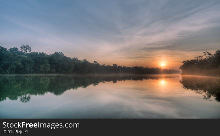 Sun crossing ridge at sunrise over a still lake