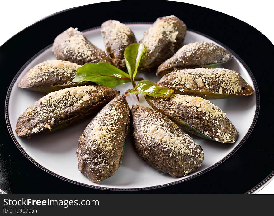 Mussels, with stuffing on a black dish.