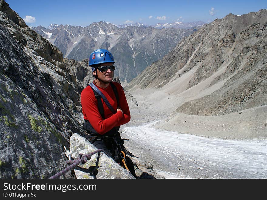 Climber in red clothes stands on a background mountains