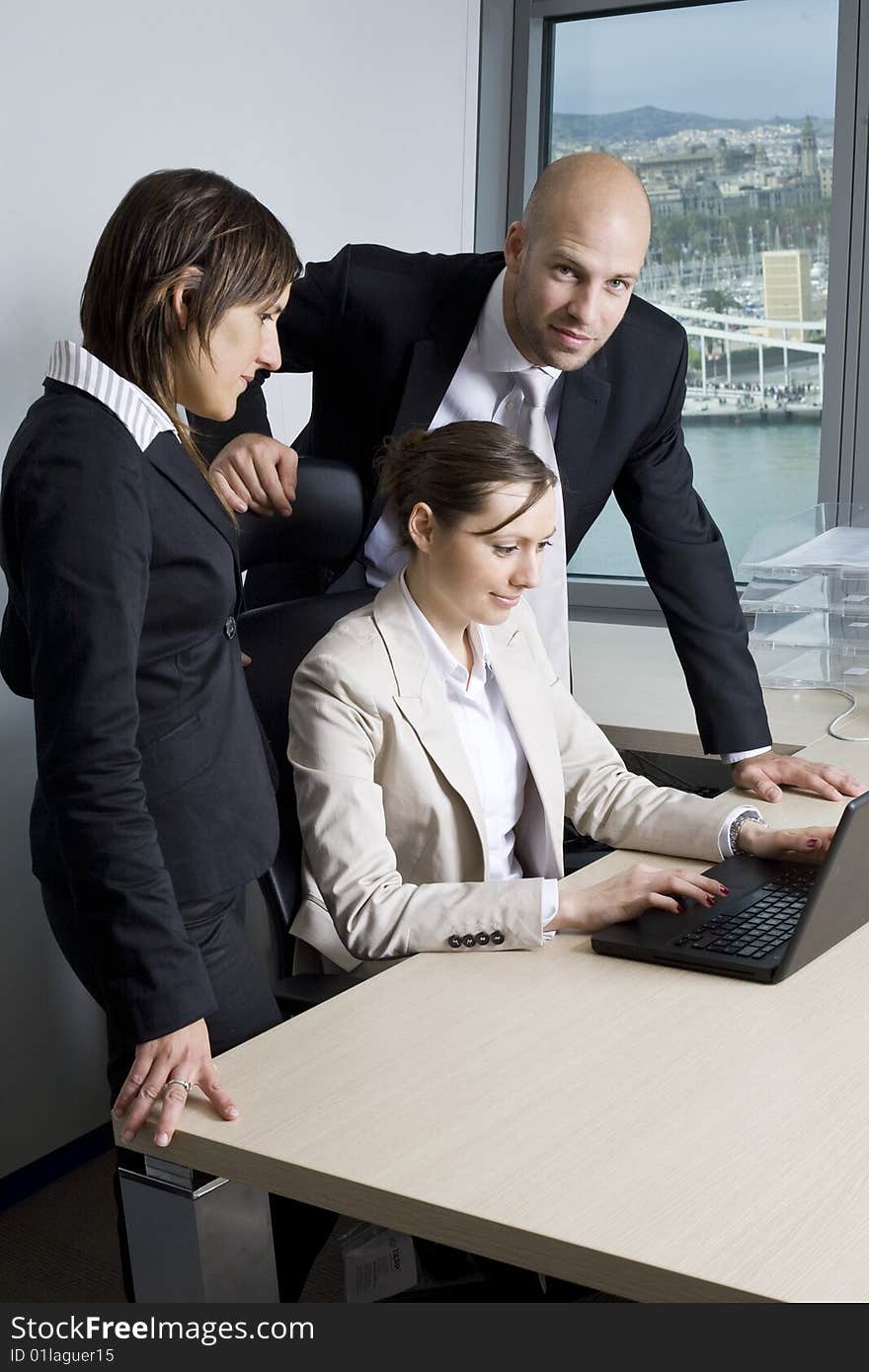 Young businessteam of three persons in office. In the background the skyline of Barcelona/Spain.