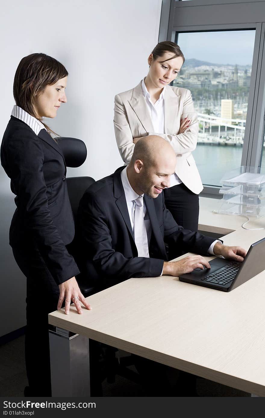 Young businessteam of three persons having fun in office. In the background the skyline of Barcelona/Spain.