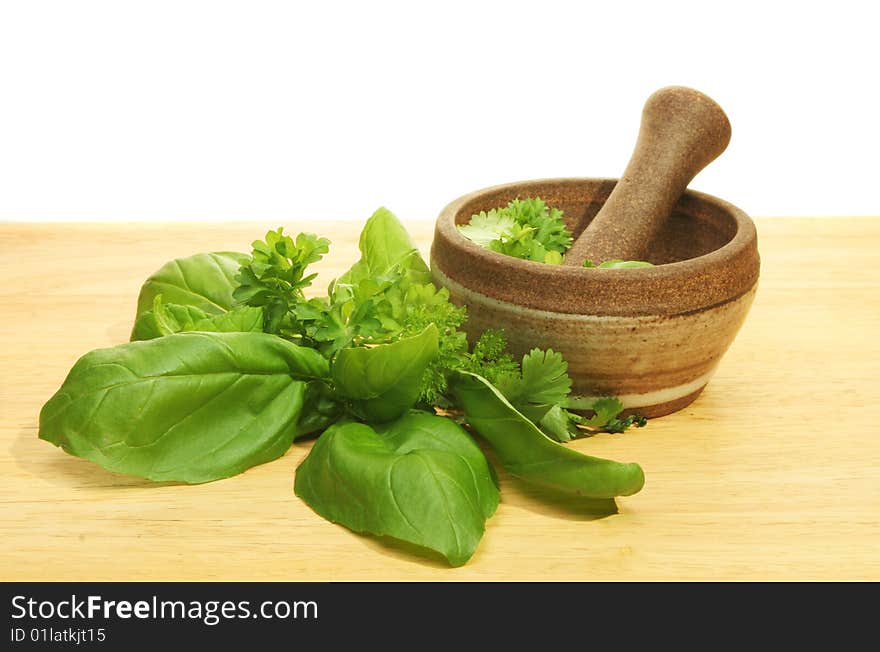 Pestle and mortar with fresh herbs on a wooden board. Pestle and mortar with fresh herbs on a wooden board