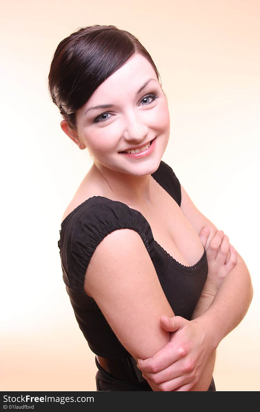 A beautiful confident young professional looking woman smiling with her arms crossed on a peach background. A beautiful confident young professional looking woman smiling with her arms crossed on a peach background.